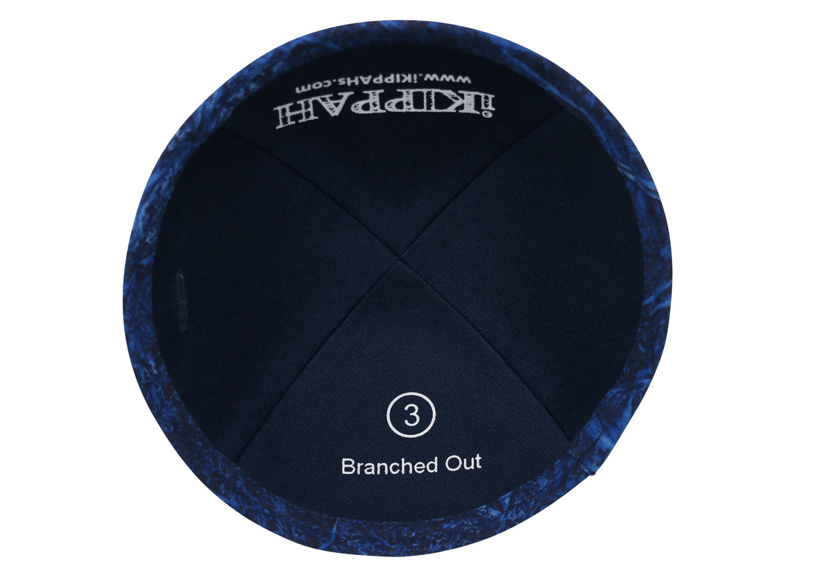 A blue iKIPPAH brand yarmulke that contains an artist's rendition of light colored branches intermingling inside view.
